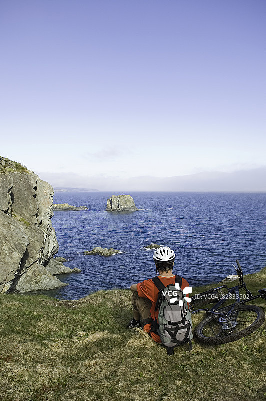 男人在海边悬崖骑山地自行车图片素材