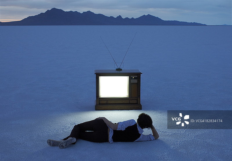 黄昏时分女人在盐滩上看电视图片素材