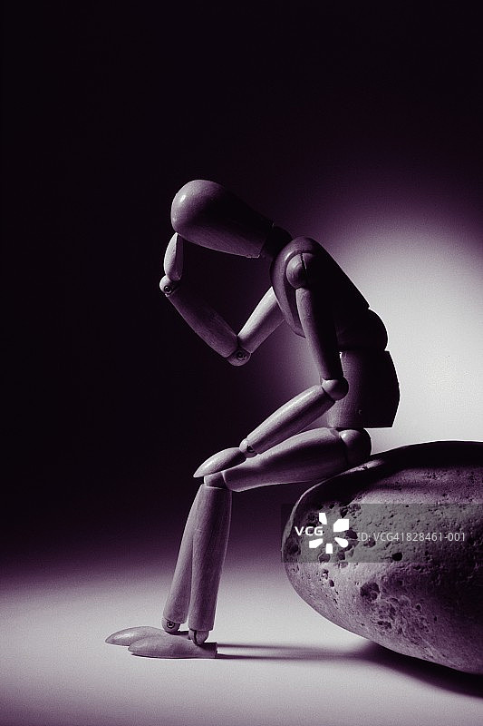 坐在岩石上，头靠在手上的绘画人偶（黑白照）图片素材