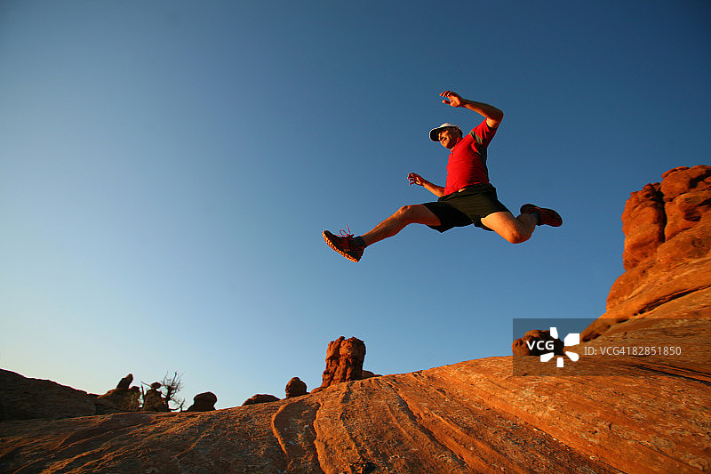男子在犹他州红岩上跳跃图片素材