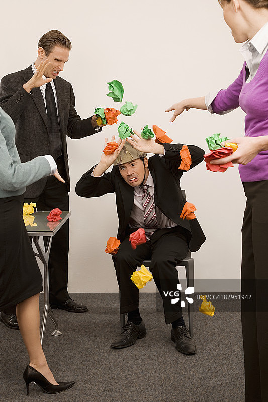 商人保护自己免受同事扔纸球的伤害图片素材