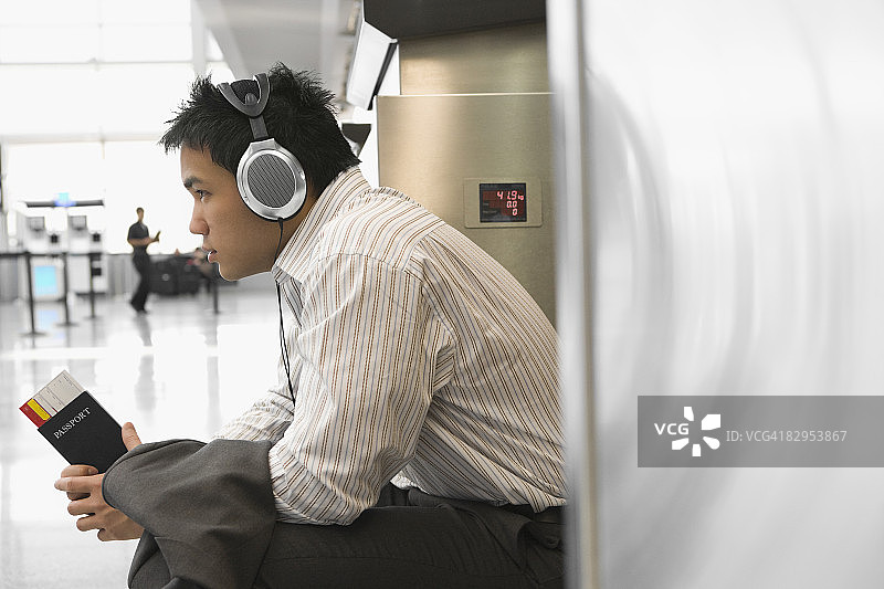 商人在机场戴着耳机听音乐的侧面轮廓照图片素材