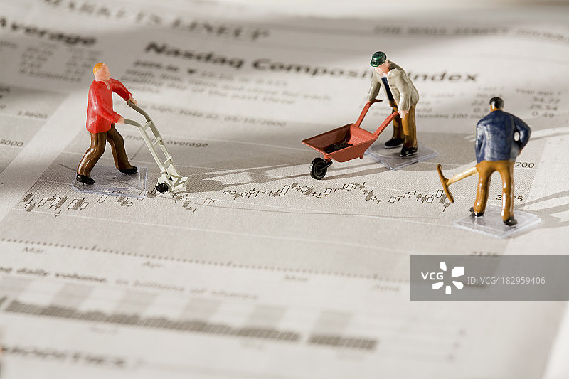 在财经报纸上工作的体力劳动者模型图片素材