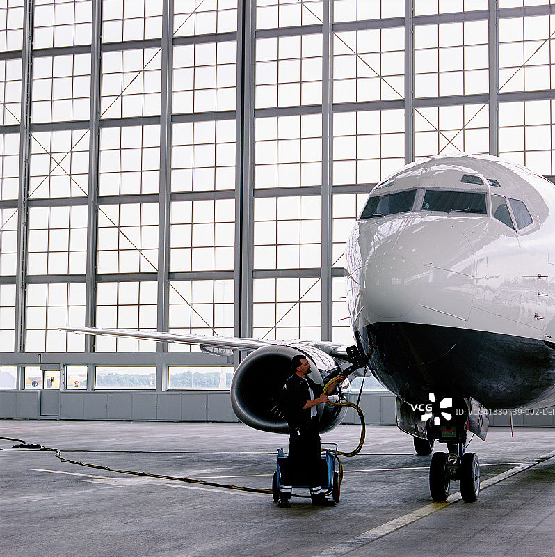 男人在机库内为商用飞机加油图片素材