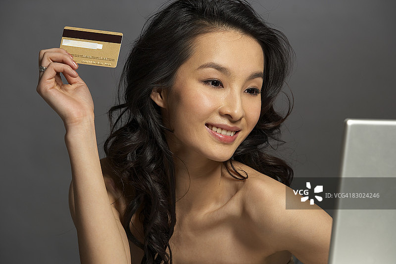 女人使用笔记本电脑，手持信用卡图片素材