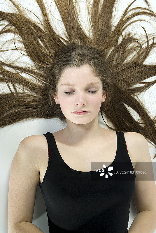 闭着眼睛的棕发女孩（13岁）肖像图片素材