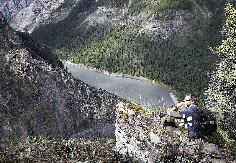 坐在悬崖上拿着相机的男人图片素材