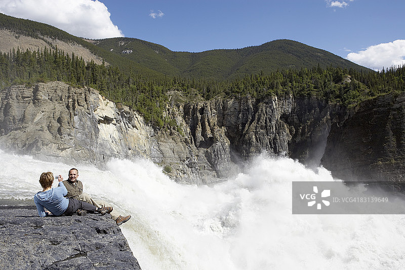 女人在瀑布附近给男人拍照图片素材