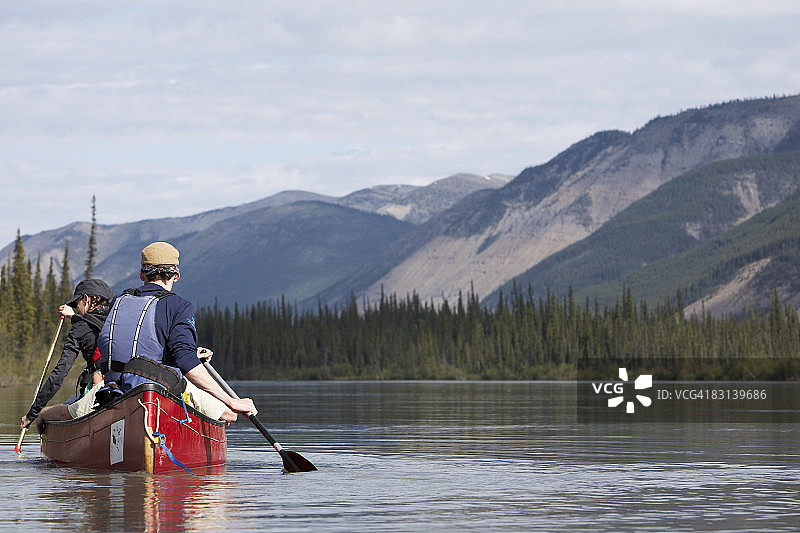 在平静水面上划独木舟的两人图片素材
