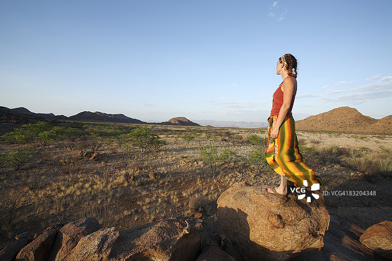 俯瞰纳米比亚考科兰红色鼓Marienfluss的岩石上的女人图片素材