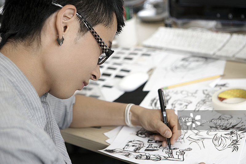年轻男人在桌前画漫画图片素材