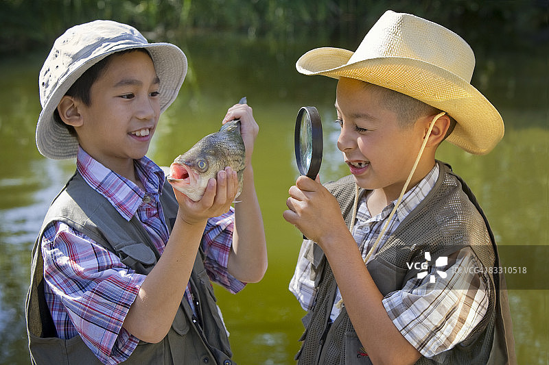 两个男孩在湖边研究捕到的鱼图片素材