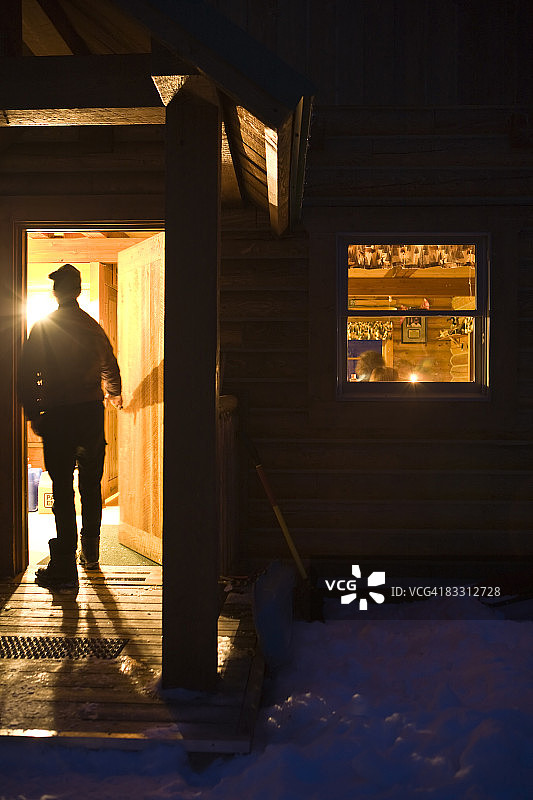 男子进入冬季木屋图片素材