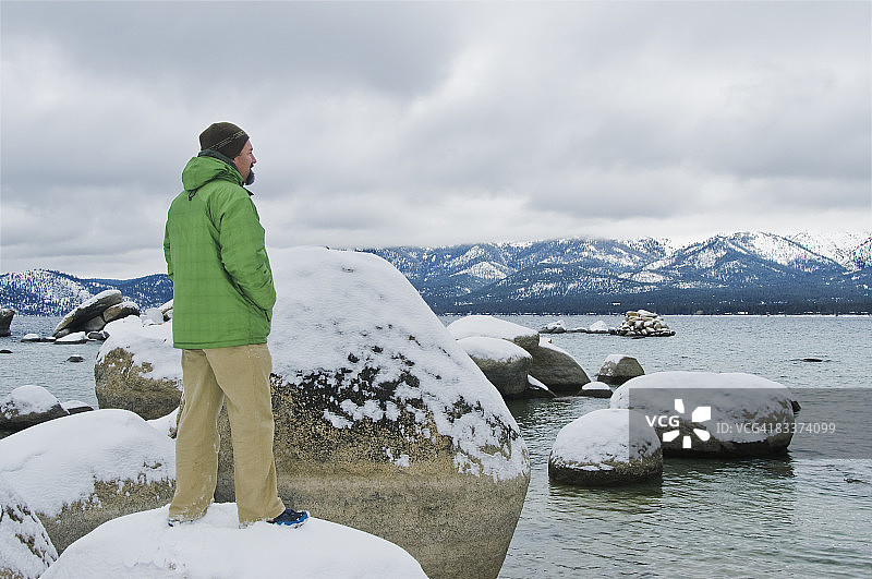 男人站在湖边的岩石上图片素材