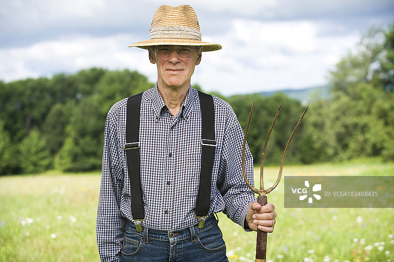 男人在田野中央手持草叉图片素材