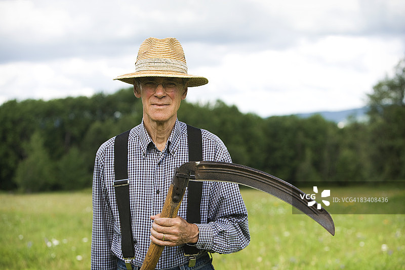 男人在田野中拿着一把镰刀图片素材