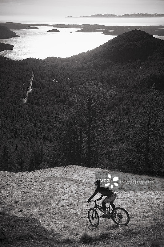 山地自行车手开始沿着俯瞰华盛顿州圣胡安群岛的斜坡下降图片素材
