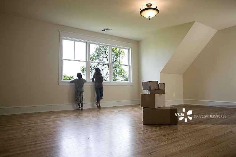 孩子们在空房间的窗户向外看图片素材