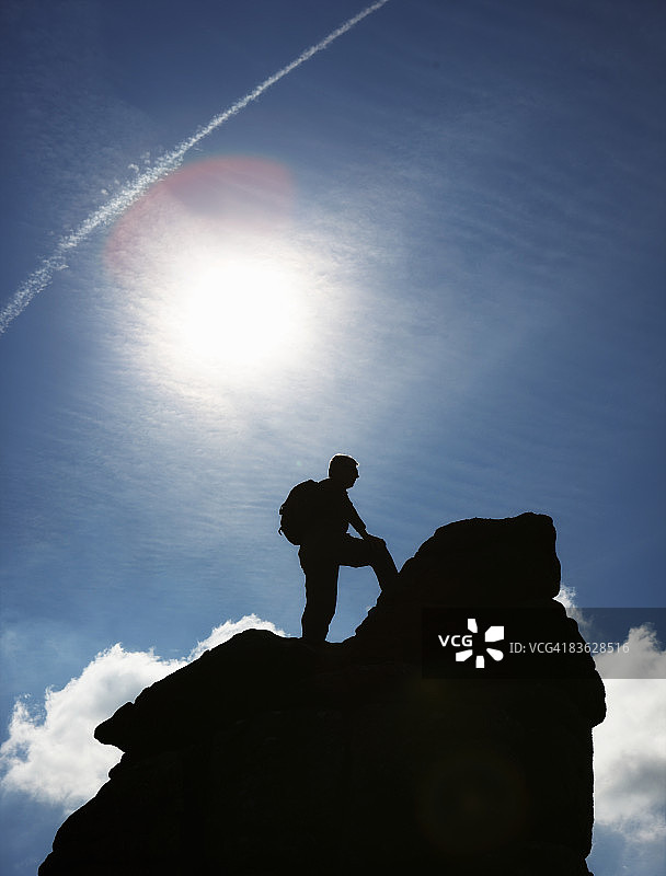 男人徒步旅行者站在高高的岩石上图片素材