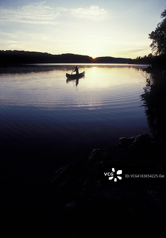 在宁静的湖面上独自划独木舟的人图片素材