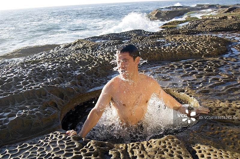 男子在沿海水坑中沐浴图片素材