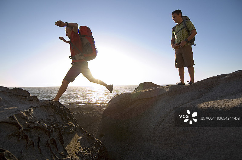 徒步者在岩石嶙峋的太平洋海岸跳跃图片素材