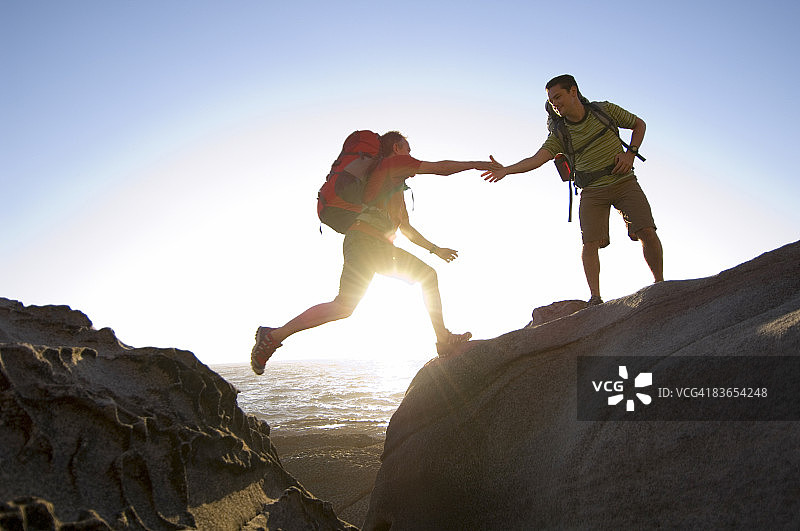 徒步者在岩石嶙峋的太平洋海岸跳跃图片素材