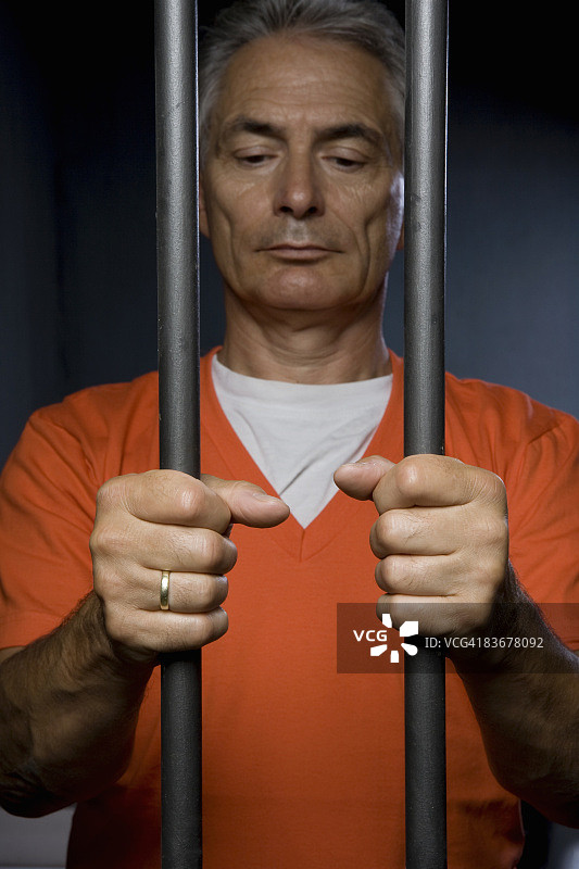 囚犯站在监狱的铁栏杆后图片素材