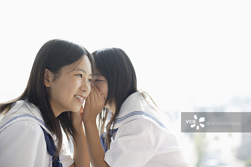 女学生在朋友耳边窃窃私语图片素材