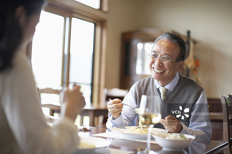 年长的男人和中年妇女一起用餐，面带微笑图片素材