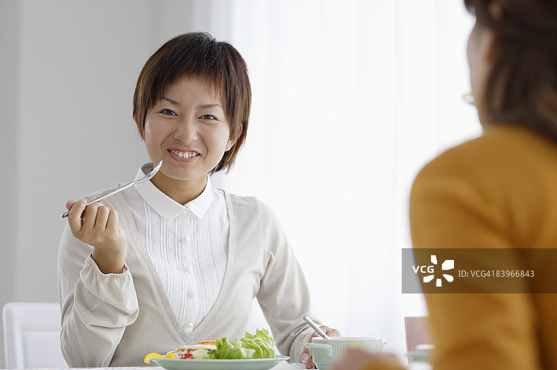 女人和朋友一起用餐，面带微笑图片素材