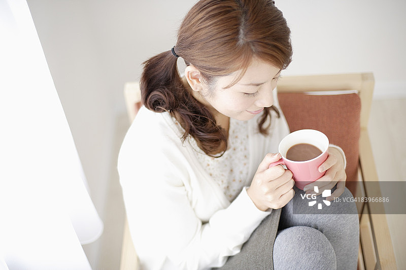 坐在椅子上喝热饮的女人图片素材