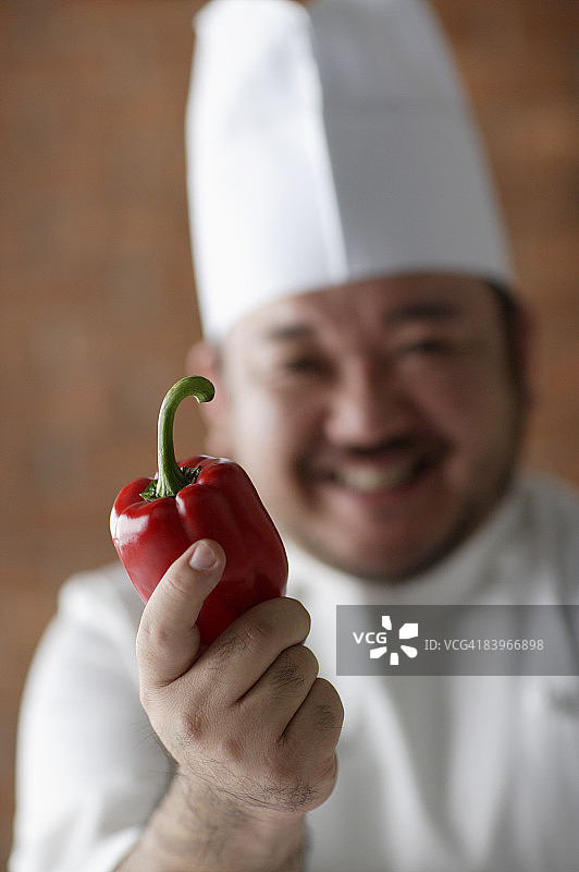 厨师手持红辣椒，焦点在红辣椒上图片素材