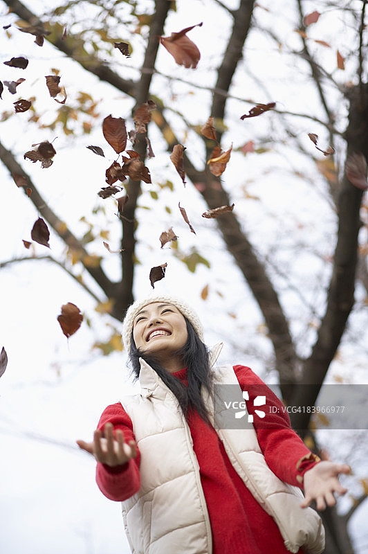 女人微笑着散落落叶图片素材