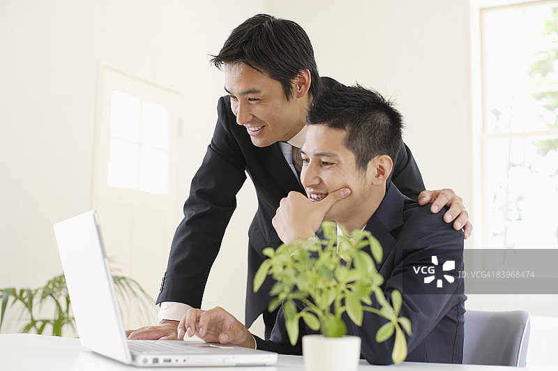 看着笔记本电脑屏幕微笑的商人图片素材
