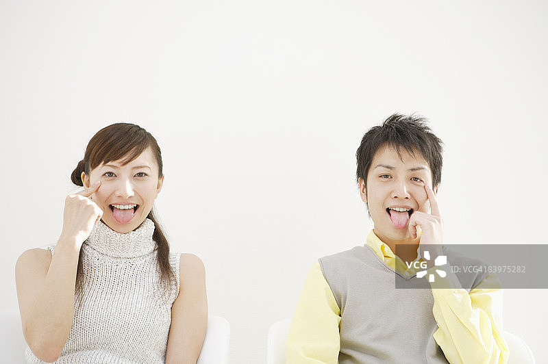 男女拉下其中一只眼睛的下眼睑并伸出舌头图片素材