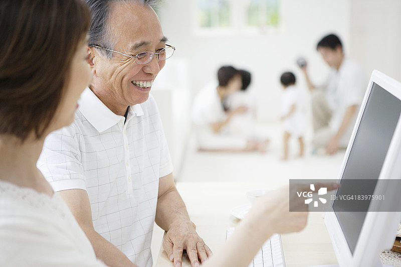 多代同堂的家庭，祖父母使用电脑，焦点在前图片素材