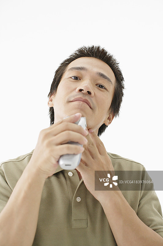 在影棚里用电动剃须刀刮胡子的男人图片素材
