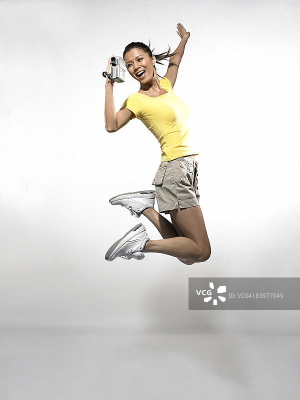 携带摄像机跳跃的女人图片素材