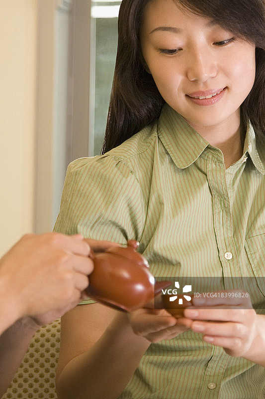 手向年轻女子手中的杯子倒茶特写图片素材