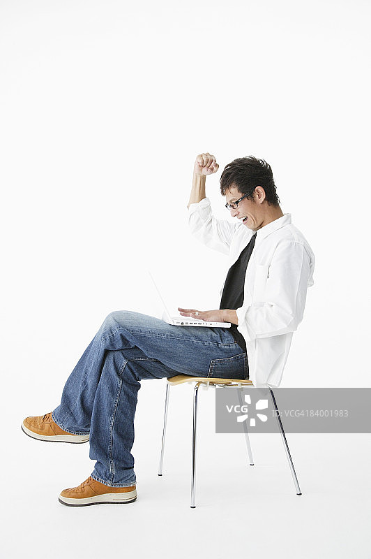 影棚中男人使用笔记本电脑举拳肖像图片素材