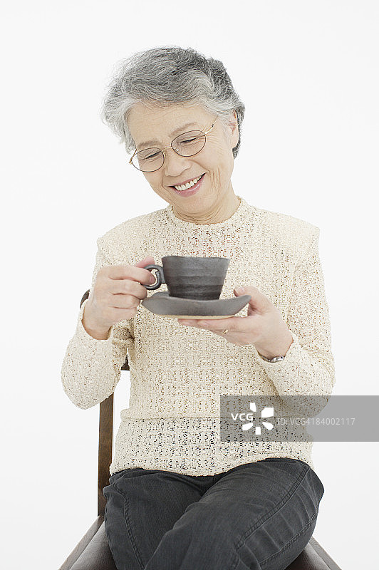 年长妇女坐在椅子上，喝咖啡的肖像，摄影图片素材