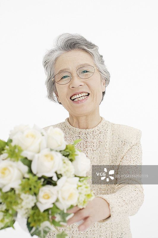 年长妇女手持一束花的肖像，特写，工作室拍摄图片素材