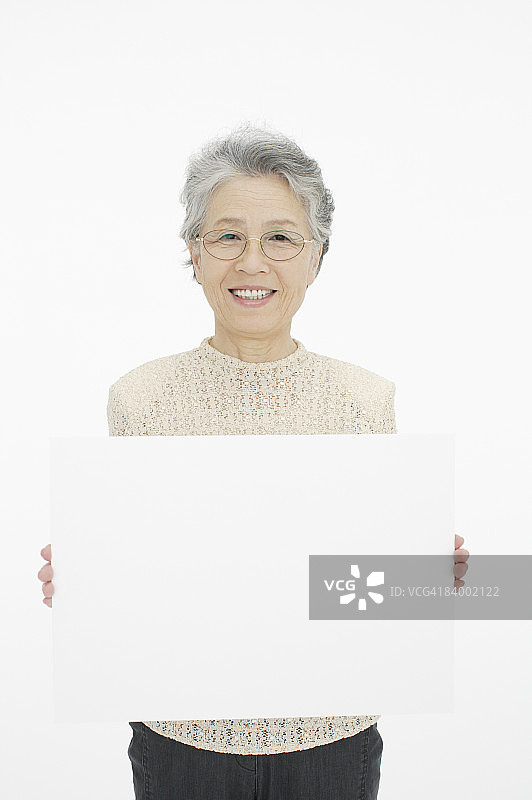手持白板的年长女人，影棚拍摄图片素材
