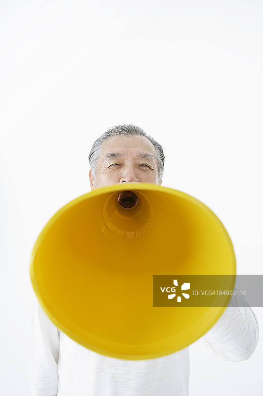 老年男人对着扩音器喊叫，工作室拍摄图片素材