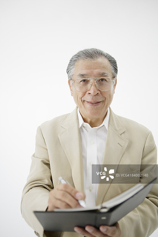 老年男人在做笔记，工作室拍摄图片素材