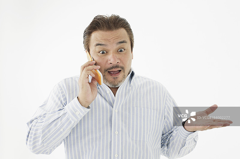 面带惊讶表情用手机交谈的男人，工作室拍摄图片素材