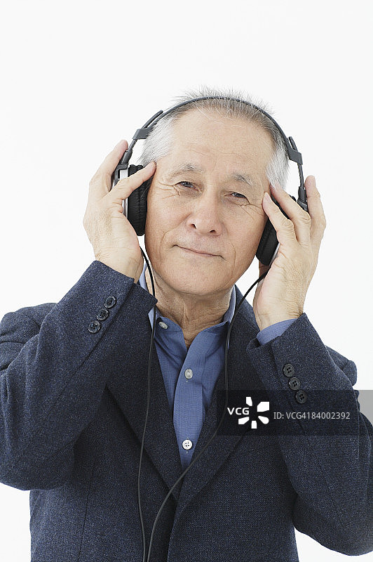 戴耳机听音乐的老年男人特写肖像，工作室拍摄图片素材