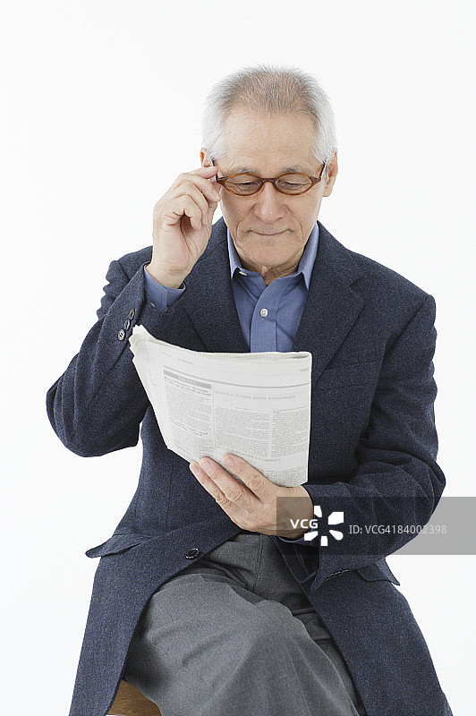 在影棚阅读报纸的年长男人肖像图片素材