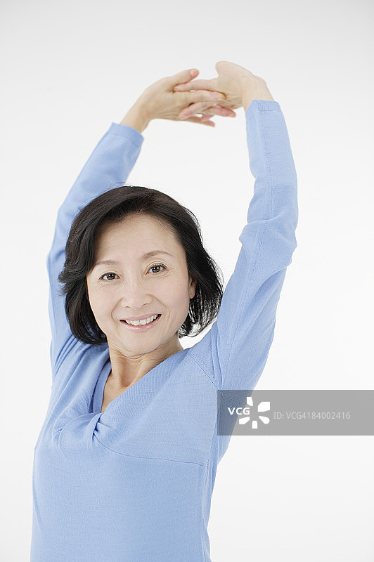 伸展双臂的女人肖像，工作室拍摄图片素材
